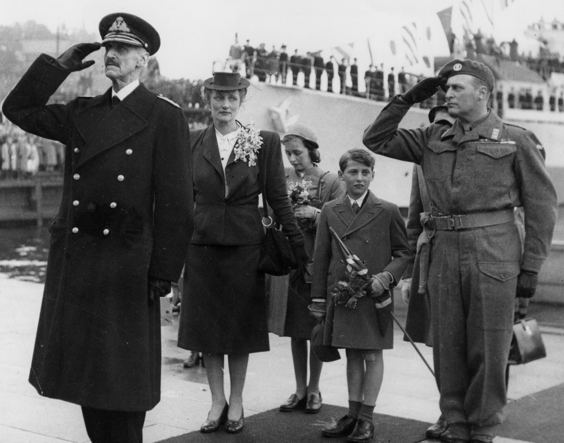 King Haakon VII salutes on the Oslo quay at the royal family's return to Norway, 7 June 1945, Crown Prince Olav saluting beside the royal children