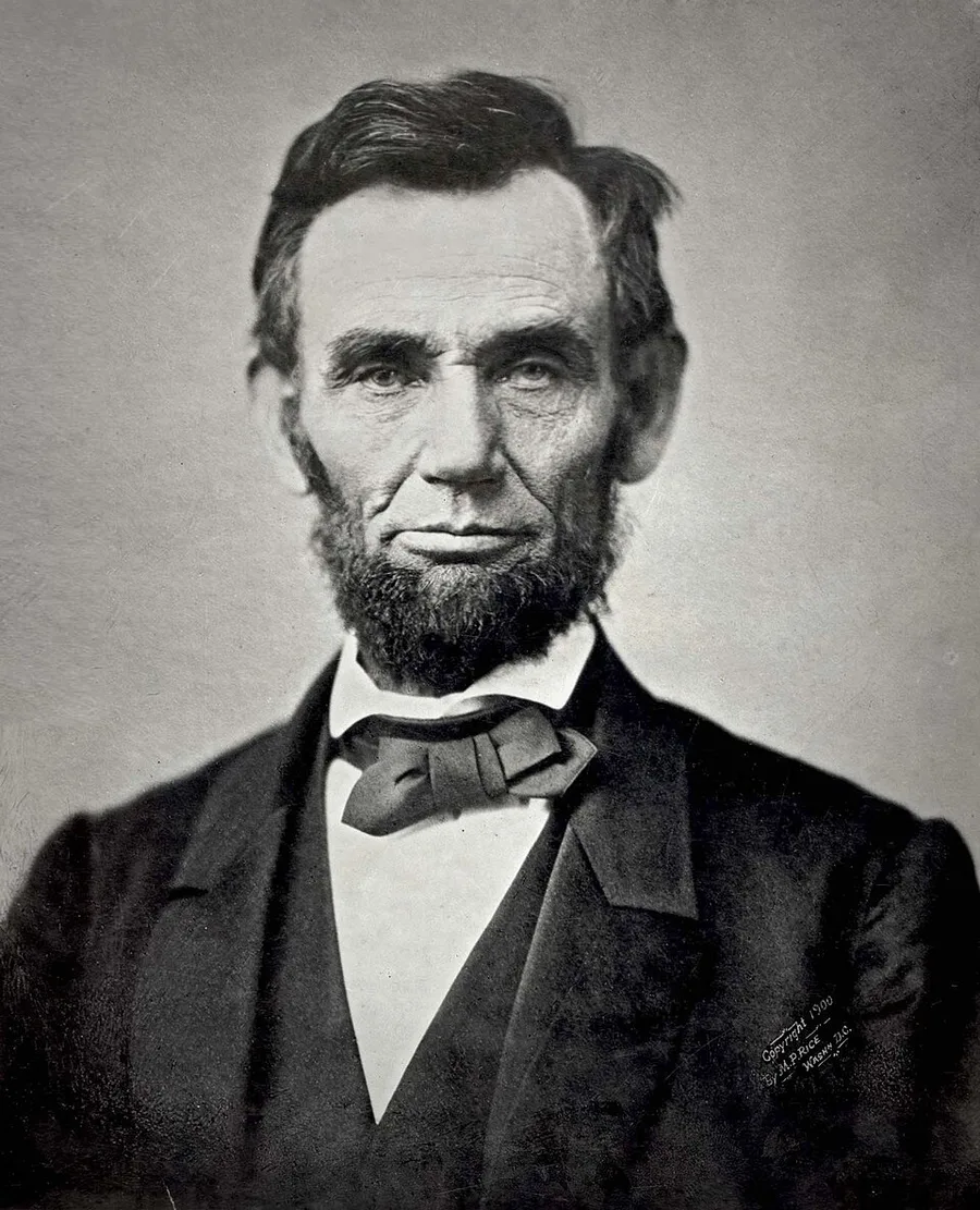 Half-length photographic portrait of a bearded Abraham Lincoln in a dark suit and bow tie, seated and facing slightly right, taken in Alexander Gardner's Washington studio in November 1863.