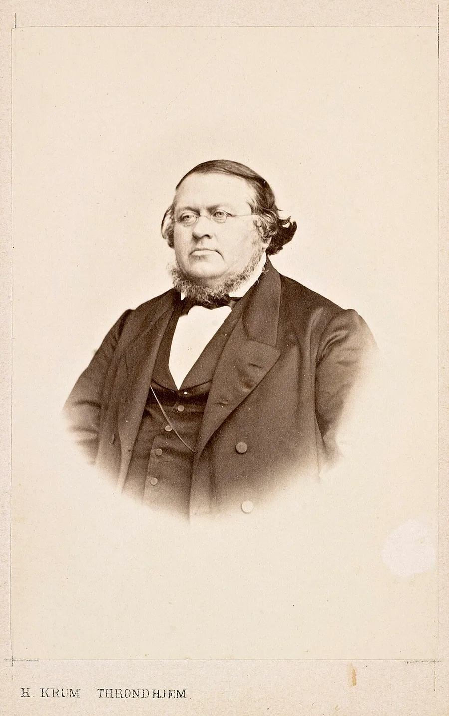 Hans Krum's carte-de-visite photograph of Peter Christen Asbjørnsen — the folktale collector heavy-set and side-whiskered in spectacles, on the Trondhjem studio's mount.