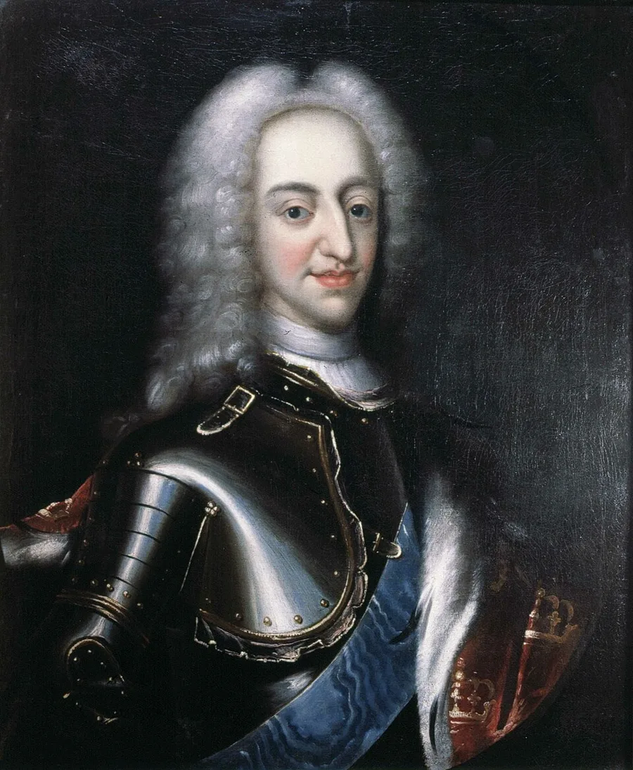 A three-quarter oil portrait of a young king with a grey curled wig, in dark steel armor and an ermine-trimmed white cape, a blue sash across his chest and a crowned red emblem at his side.