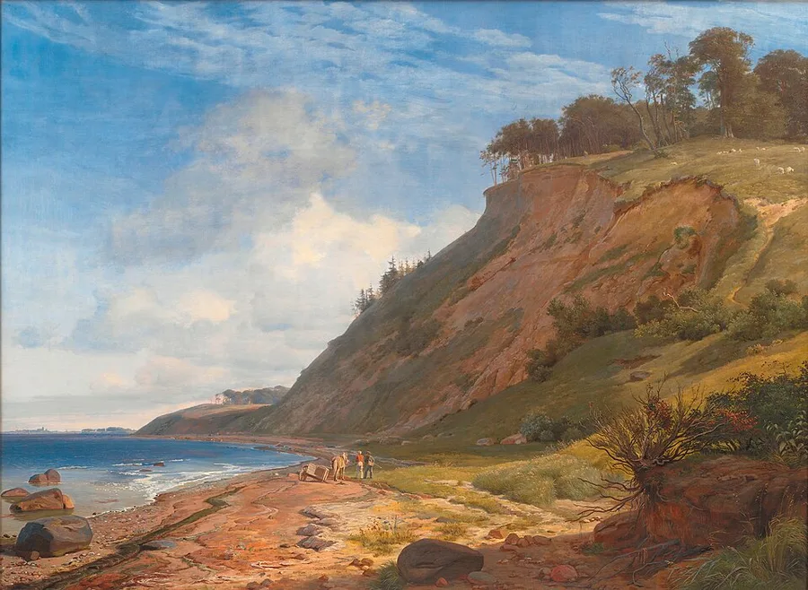 Oil painting of a Danish coast: a high clay cliff edged with trees and grazing sheep rises over a stony beach, where two figures with a white horse and cart pause on the shore road beside calm blue water stretching to a low far shore.
