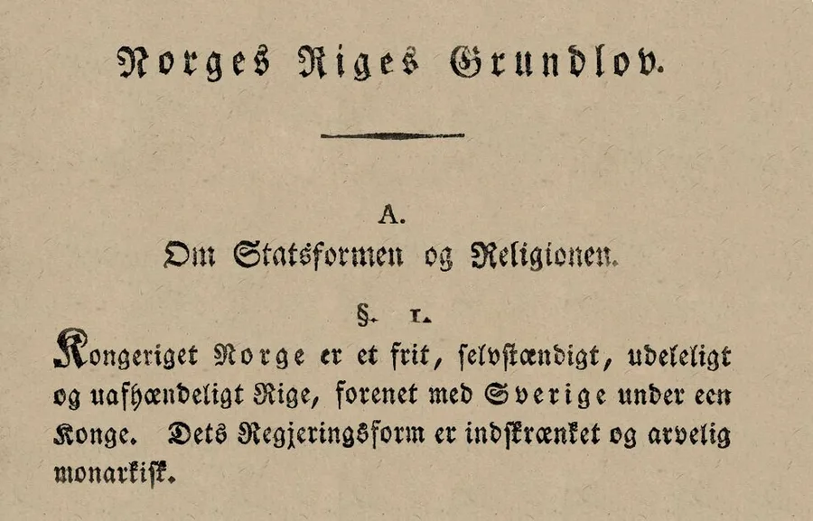 The heading and first article of the printed 1814 Norwegian Constitution in Fraktur type: Norges Riges Grundlov, the section Om Statsformen og Religionen, and §1 in its November wording — a free, independent, indivisible and inalienable realm, united with Sweden under one King.