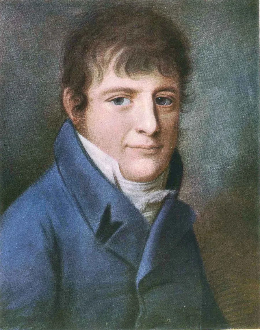 Painted portrait of a young man with curly brown hair in a blue coat and white cravat, looking slightly to the side against a plain grey-brown background; no medals or decorations visible.