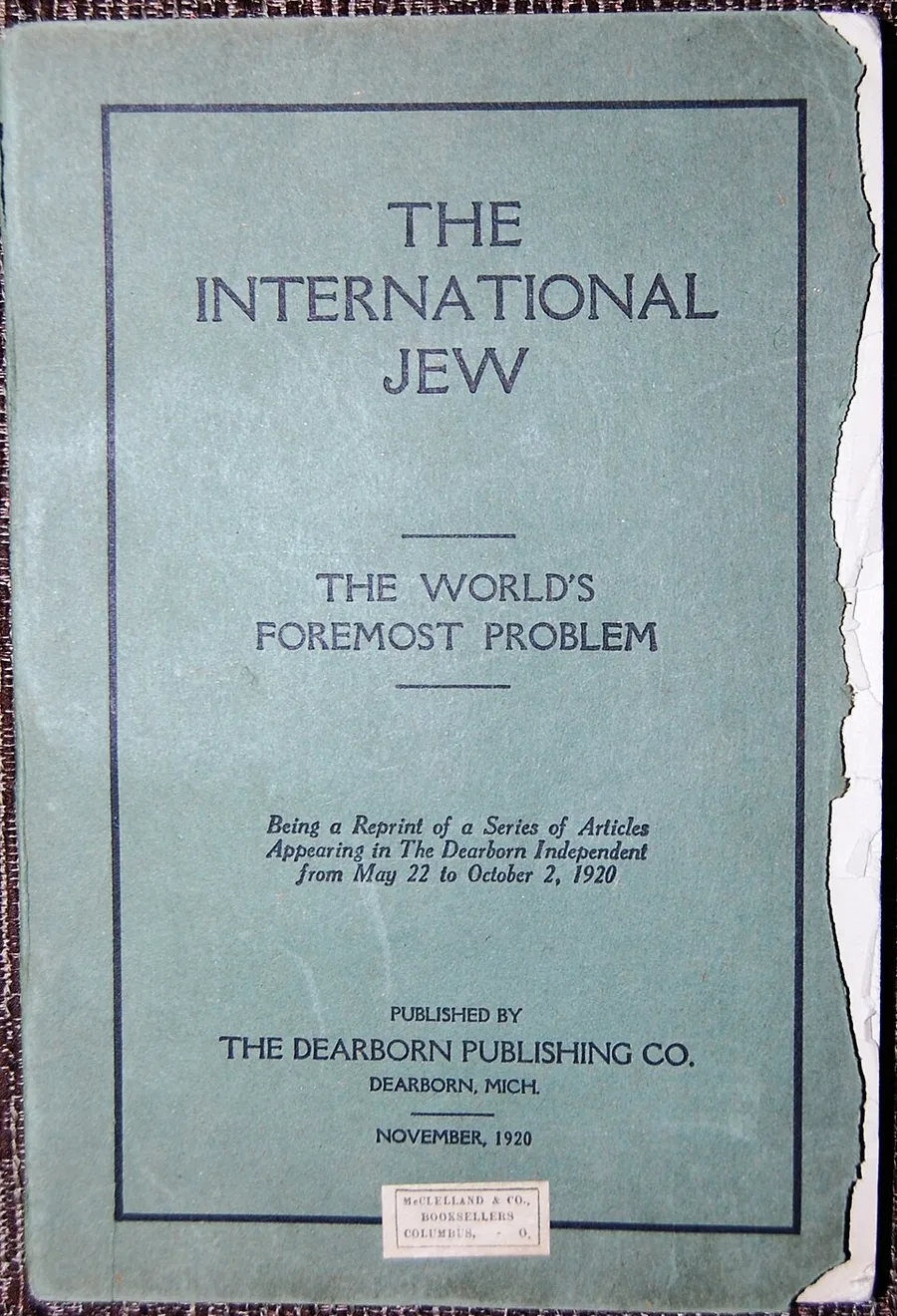 Photograph of the worn cloth cover of the November 1920 first edition of The International Jew, with its title, subtitle "The World's Foremost Problem," and Dearborn Publishing Co. imprint legible.