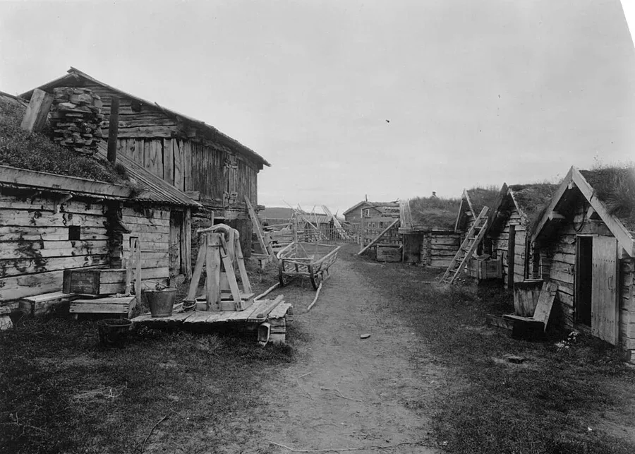 Anders Beer Wilse's 1933 photograph of Karasjok — two rows of low timber houses with turf roofs flanking the dirt village road.