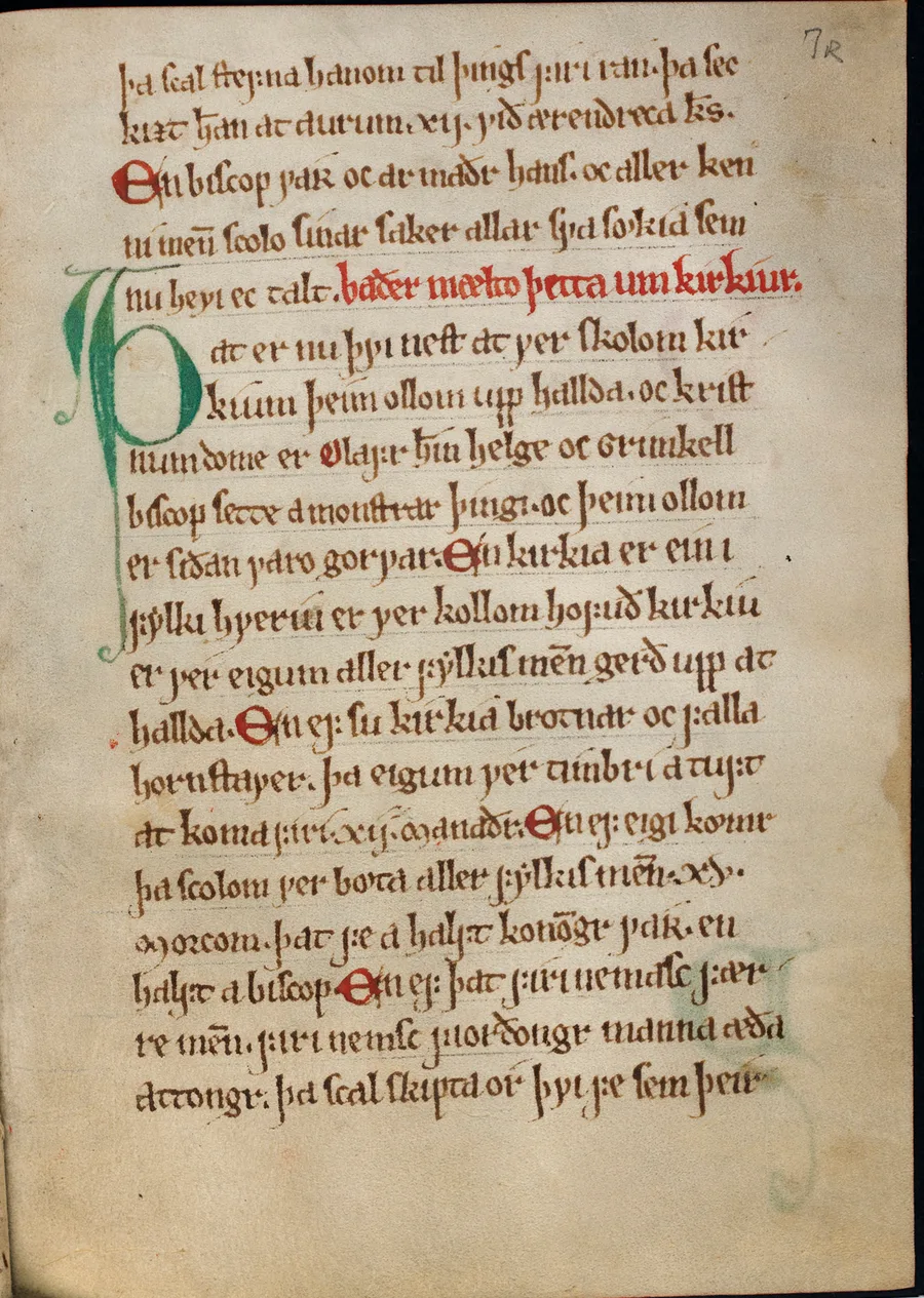 Vellum manuscript page of medieval Norwegian text in brown ink, with one rubric line in red, a tall green initial thorn in the margin, and the folio mark 7r in the top corner.