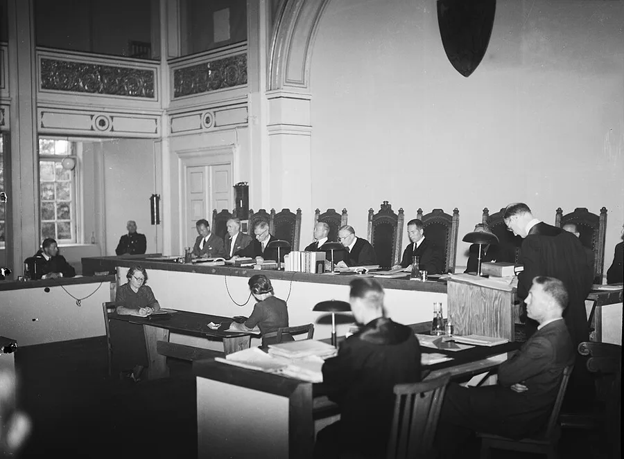Black-and-white courtroom photograph from 1945: judges in robes seated behind a long bench in a formal chamber, with clerks, a stenographer, and other officials at tables in the foreground.