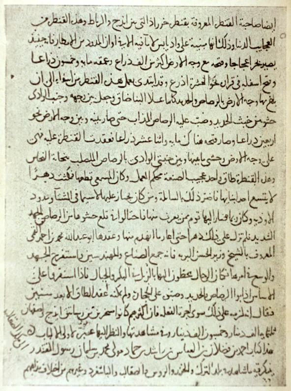 A page of dense Arabic manuscript in black naskh script on warm-toned paper, the lines slightly slanting, with a diagonal marginal note at the lower left — from a 13th-century copy of Ibn Fadlan's Risala.