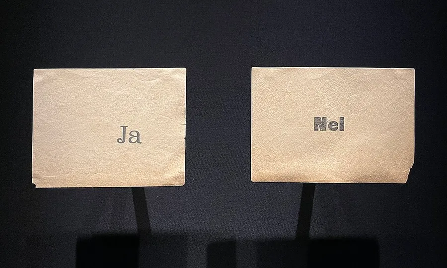 Two aged paper ballots displayed side by side under glass, one printed 'Ja' and the other 'Nei' — the actual ballot papers from Norway's 12-13 November 1905 referendum on monarchy versus republic.
