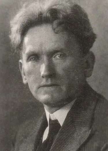 Black-and-white halftone portrait from around 1930: Olav Gullvåg in middle age, thick hair swept back from a high forehead, serious gaze at the camera, wearing a tweed jacket, white collar and dark tie.