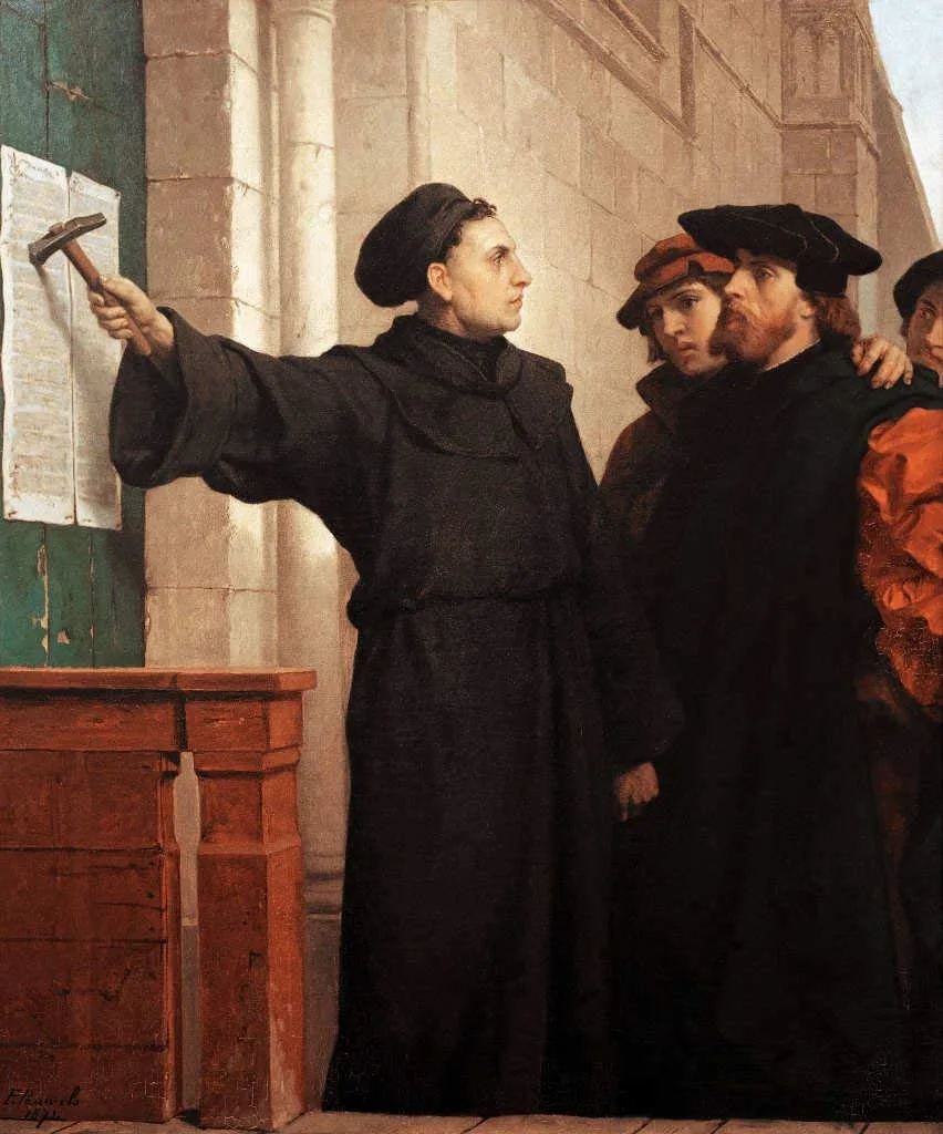 1872 history painting: Martin Luther, in a dark monk's robe and cap, hammers a printed sheet to a church door while a small group of onlookers in period dress watches from behind him.
