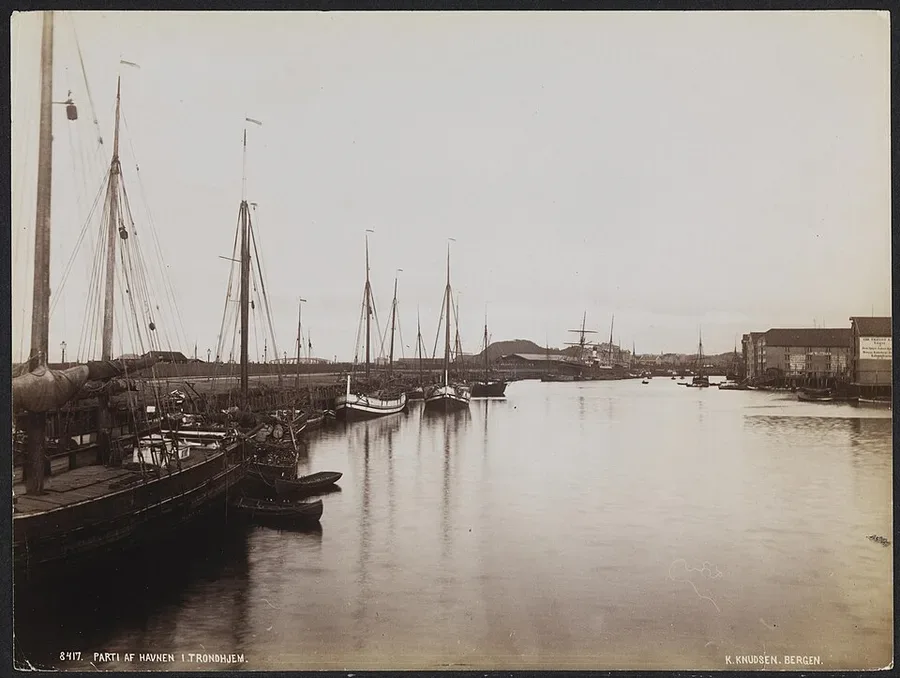 Knud Knudsen's photograph of Trondheim harbour in the early 1890s — masts and moored sloops along the wharf-houses of the Nidelva.