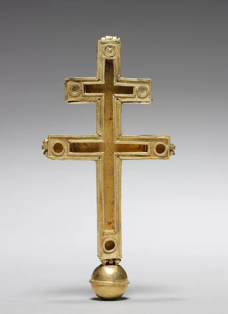 A studio photograph of a plain gilded double-armed cross (a longer lower bar, shorter upper bar) with a round finial ball at its base and small drilled settings along each arm, now empty of stones, against a gray gradient background.